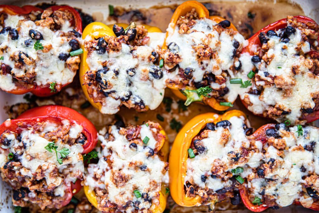 bell peppers, stuffed bell peppers, ground chicken, melted cheese, white dish, black beans