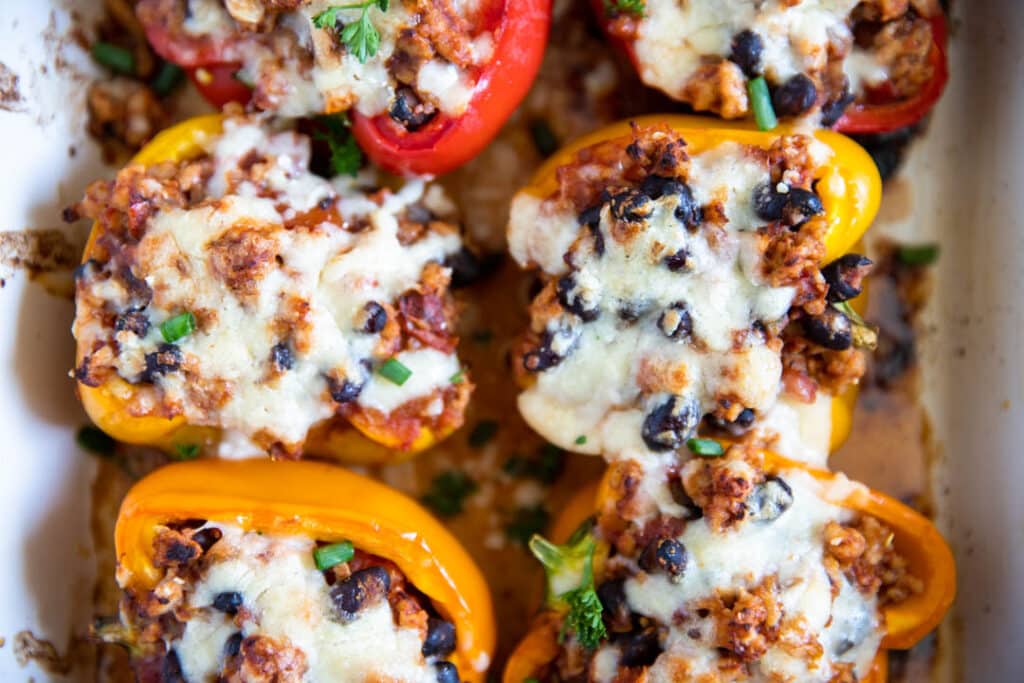 bell peppers, stuffed bell peppers, ground chicken, melted cheese, white dish, black beans