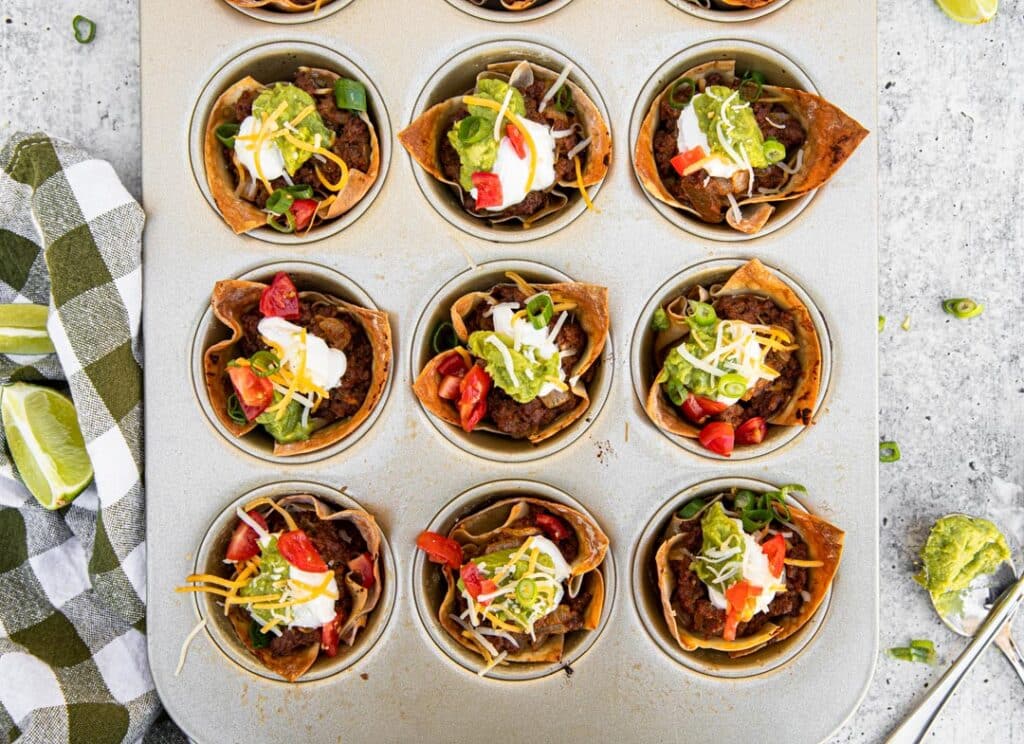 checkered towel, limes, guacamole, taco cups, muffin tin, taco meat